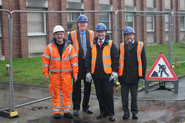image of four men in front of police station which is fenced off