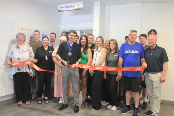 The Vice Chair of Lichfield District Council Councillor Andrew Rushton cuts the ribbon to open the new changing village at Burntwood Leisure Centre as staff members and centre users look on.