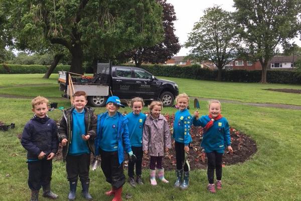 Seven beavers pose by flowerbed