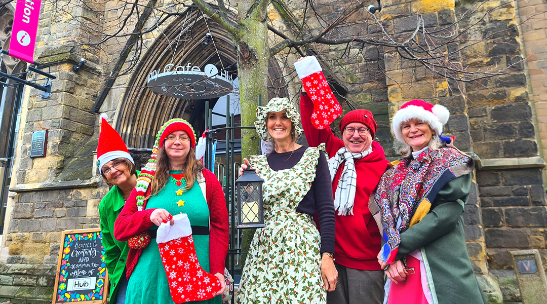 tour guides dressed in Christmas costumes holding stockings in front of St Mary's