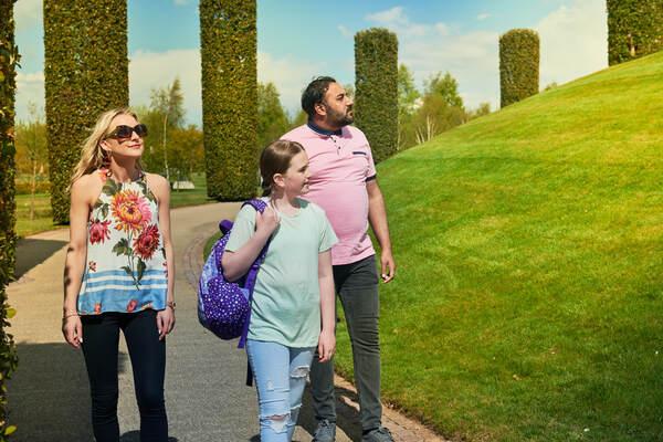 A family of three walking on the path at the National Memorial Arboretum