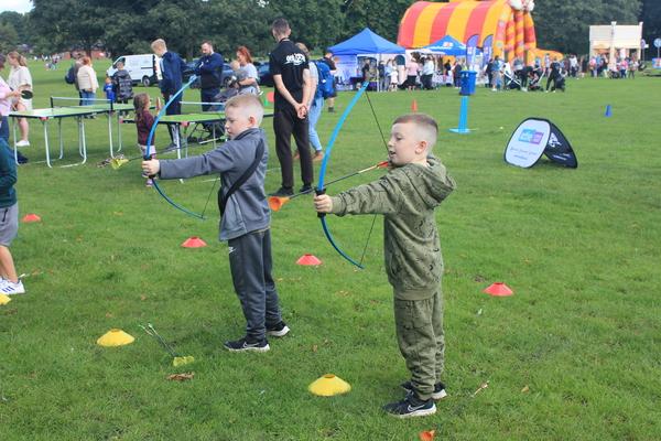 Two boys aiming toy bow and arrows on the grass at a fun day