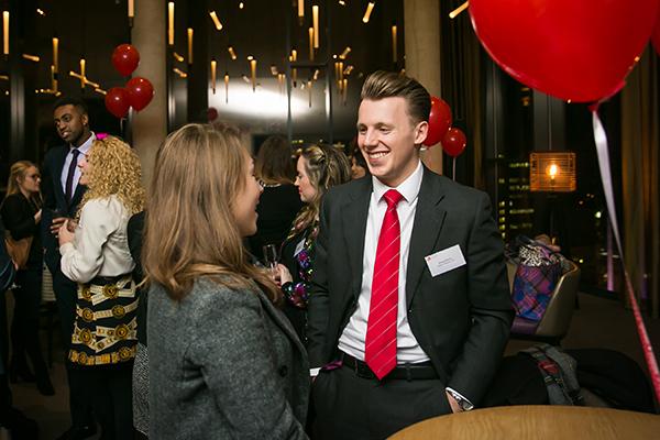 young man and woman in suits talk together