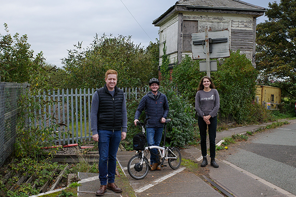 Two men and a woman stand on old railway line crossroads