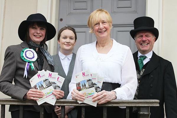Three women dressed as suffragettes and a man in turn of the century clothes