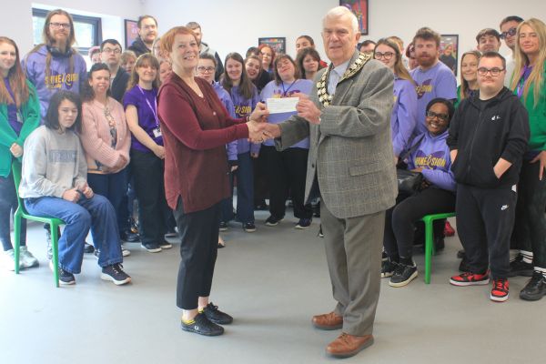 A picture of Maggi Huckfield, CEO of Liberty Jamboree being presented with a cheque by the Chair of Lichfield District Council Councillor Keith Vernon while Liberty Jamboree members and staff look on.