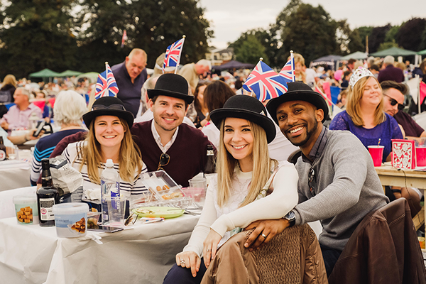 two young couples sat at proms table wearing bowler hats
