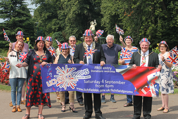 sponsors gather in park in front of proms banner