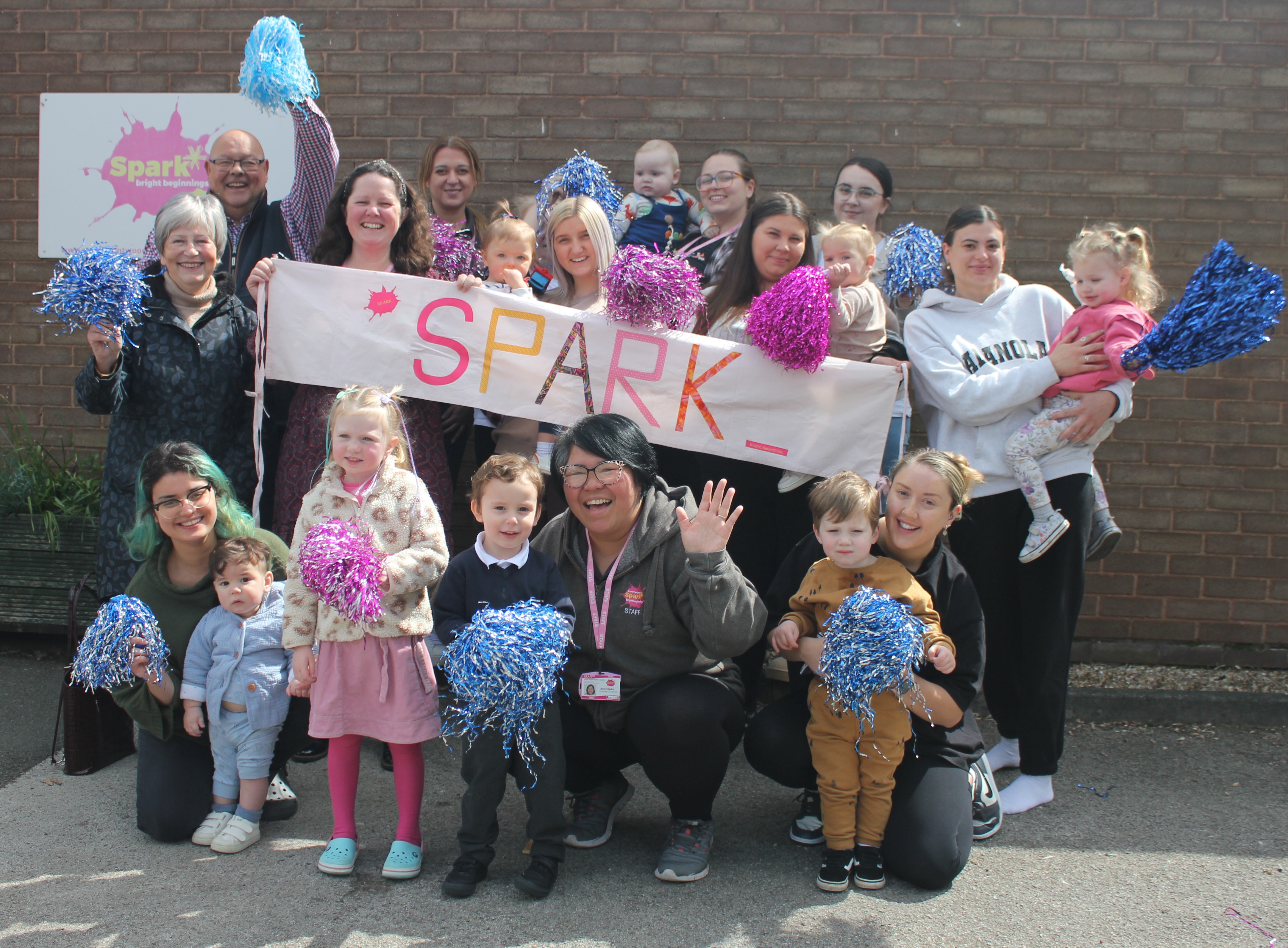 A photo of Lichfield District Council’s Cabinet Member for Community Engagement Councillor Richard Cox (back left) with Spark’s Chief Officer Esther Allen (middle, second from left), fellow staff and some mums and children who attend the centre.
