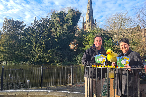 Man and woman stand in front of cathedral with duck soft toy and mini rubber ducks