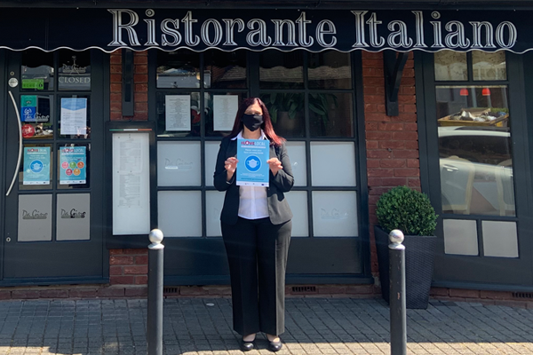 woman in face mask outside restaurant holding face mask poster