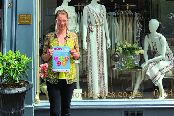 woman holding Love Local poster outside fashion window display