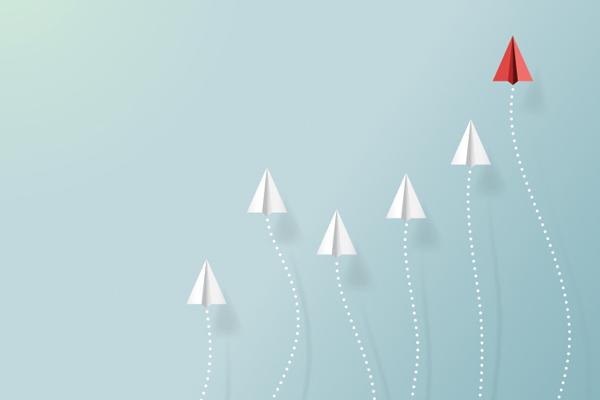 illustration of paper aeroplanes flying upwards with a red one winning