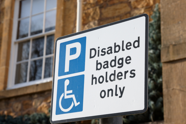 A white parking sign reading Disabled badge holders only.