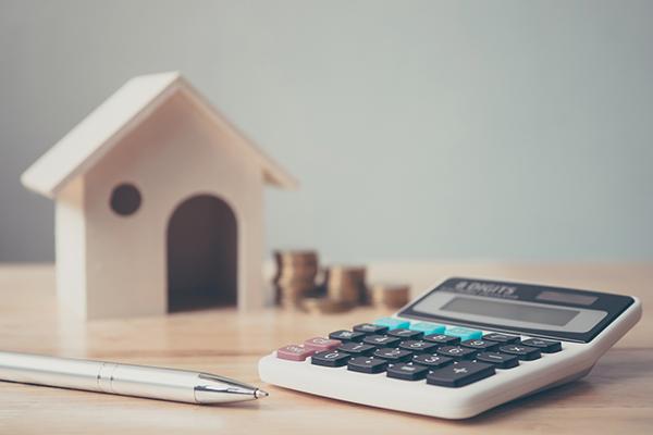 wooden house next to money and a calculator